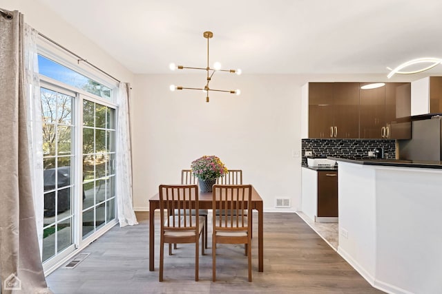 dining area featuring a notable chandelier, visible vents, baseboards, and wood finished floors