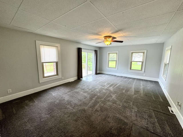 unfurnished room featuring baseboards, ceiling fan, a drop ceiling, and dark carpet