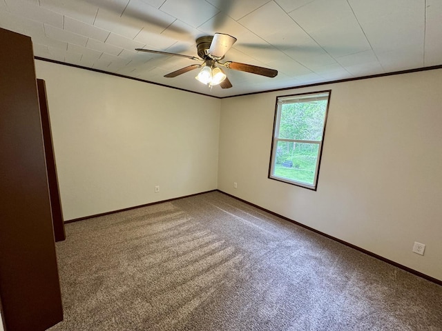 carpeted empty room featuring crown molding, baseboards, and a ceiling fan