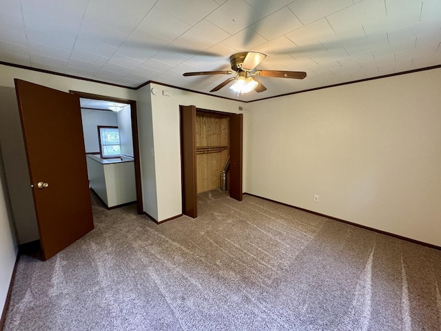 unfurnished bedroom featuring crown molding, a ceiling fan, baseboards, and carpet