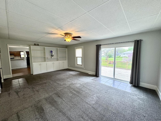 unfurnished living room with baseboards, a ceiling fan, dark carpet, and visible vents