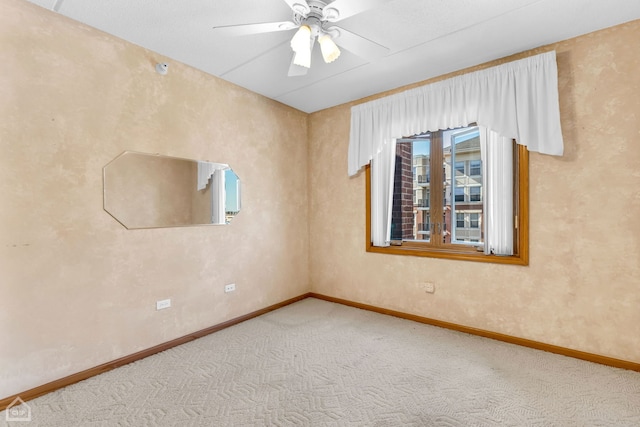 carpeted empty room featuring ceiling fan and baseboards