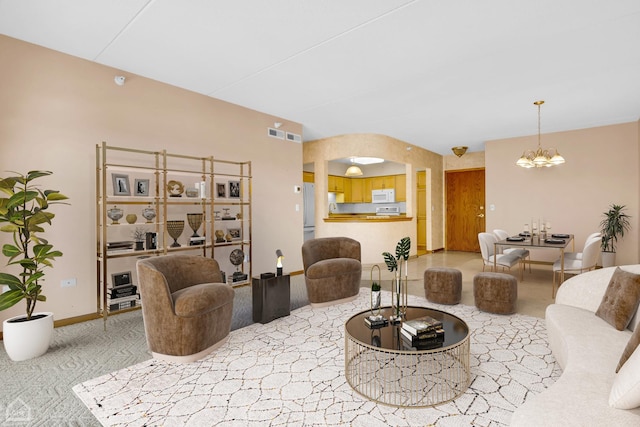 living room with a chandelier, arched walkways, light colored carpet, visible vents, and baseboards