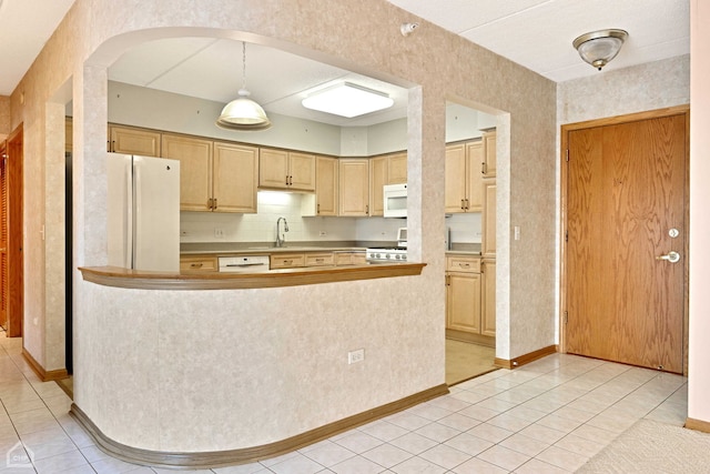 kitchen featuring white appliances, light tile patterned flooring, a sink, and light brown cabinetry