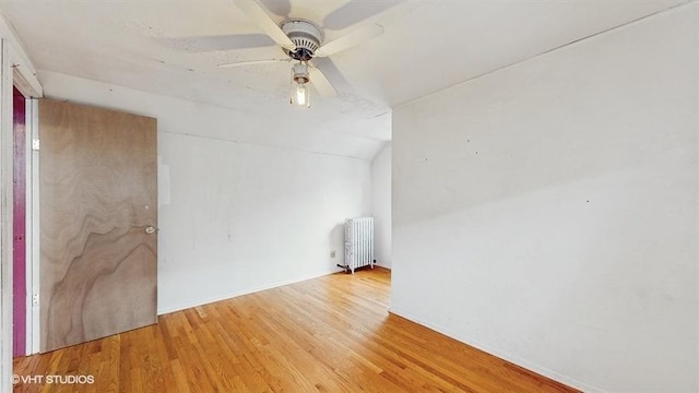 spare room featuring radiator, a ceiling fan, wood finished floors, and lofted ceiling