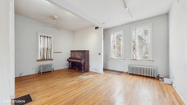 interior space with track lighting, radiator, visible vents, and light wood finished floors