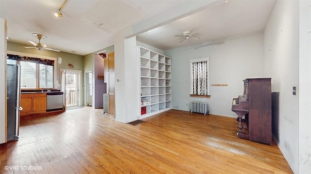 unfurnished room featuring radiator, light wood-style flooring, and a ceiling fan