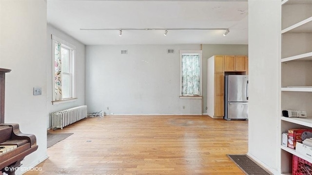 living room with track lighting, visible vents, light wood finished floors, and radiator heating unit