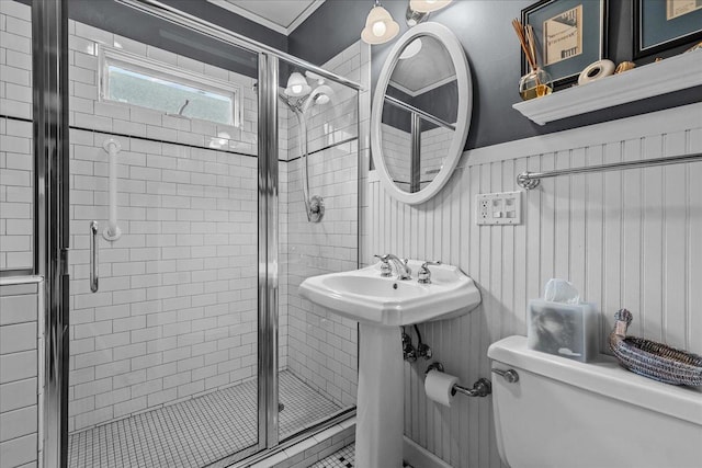 bathroom with wainscoting, a stall shower, toilet, and a sink