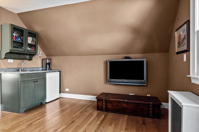 interior space featuring baseboards, light wood-style floors, and lofted ceiling