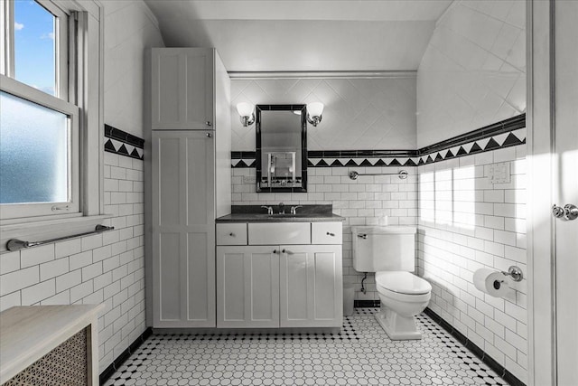 bathroom featuring plenty of natural light, toilet, and tile walls