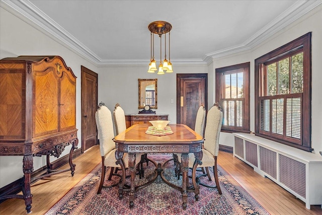 dining space with light wood-style flooring, radiator, and crown molding