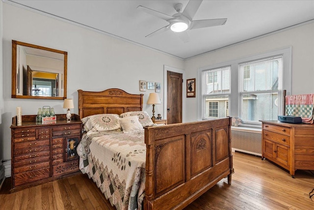 bedroom with light wood finished floors, radiator, and a ceiling fan