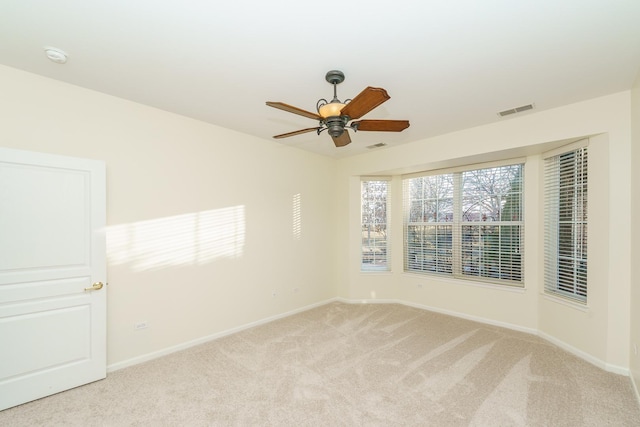 unfurnished room with baseboards, ceiling fan, visible vents, and light colored carpet