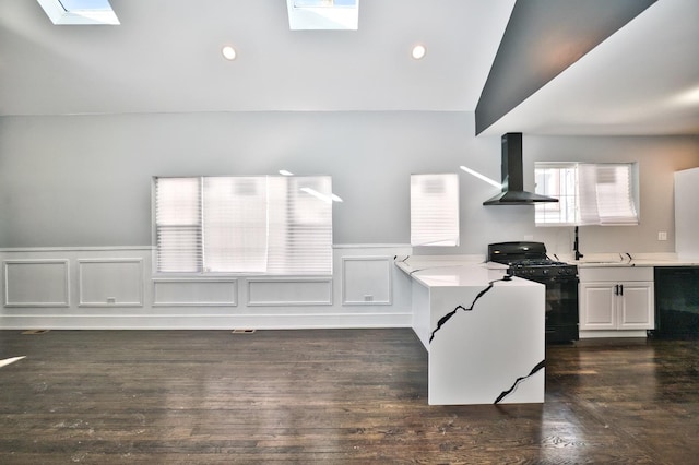 kitchen with vaulted ceiling with skylight, dark wood-type flooring, light countertops, wall chimney range hood, and black appliances