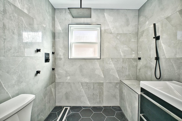 full bath with a tile shower, tile walls, and toilet