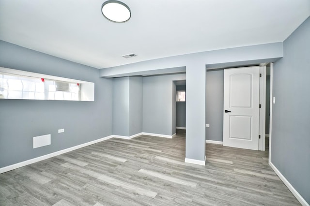 below grade area featuring wood finished floors, visible vents, and baseboards