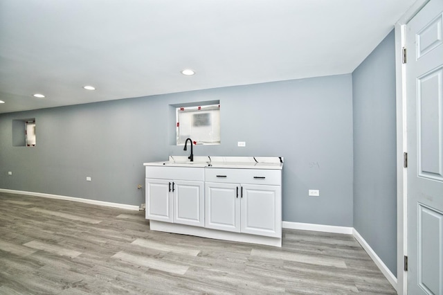 interior space with recessed lighting, baseboards, a sink, and light wood finished floors