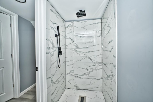 bathroom with wood finished floors, a marble finish shower, and baseboards