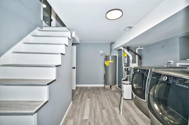 clothes washing area with water heater, washing machine and dryer, light wood-type flooring, laundry area, and baseboards