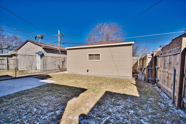 back of property featuring a fenced backyard, a yard, and an outdoor structure