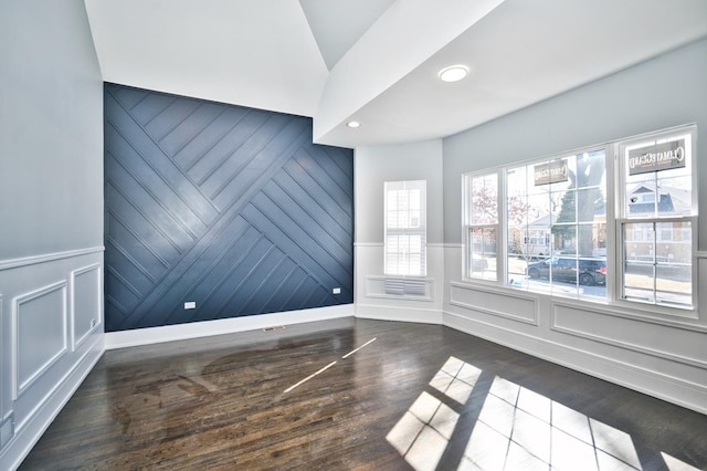 empty room with recessed lighting, a decorative wall, and wood finished floors