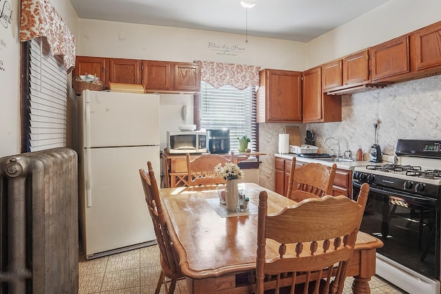 kitchen with stainless steel microwave, freestanding refrigerator, light countertops, a sink, and gas stove