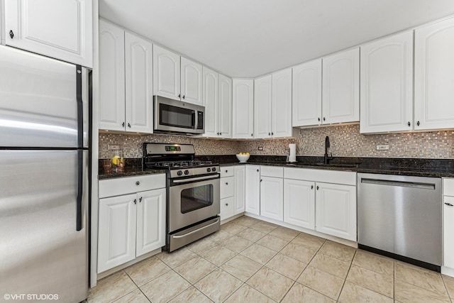 kitchen featuring stainless steel appliances, a sink, decorative backsplash, and dark stone countertops