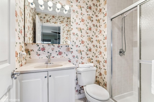 full bathroom with vanity, a shower stall, toilet, and wallpapered walls