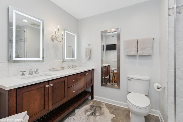 bathroom with double vanity, baseboards, decorative backsplash, toilet, and a sink