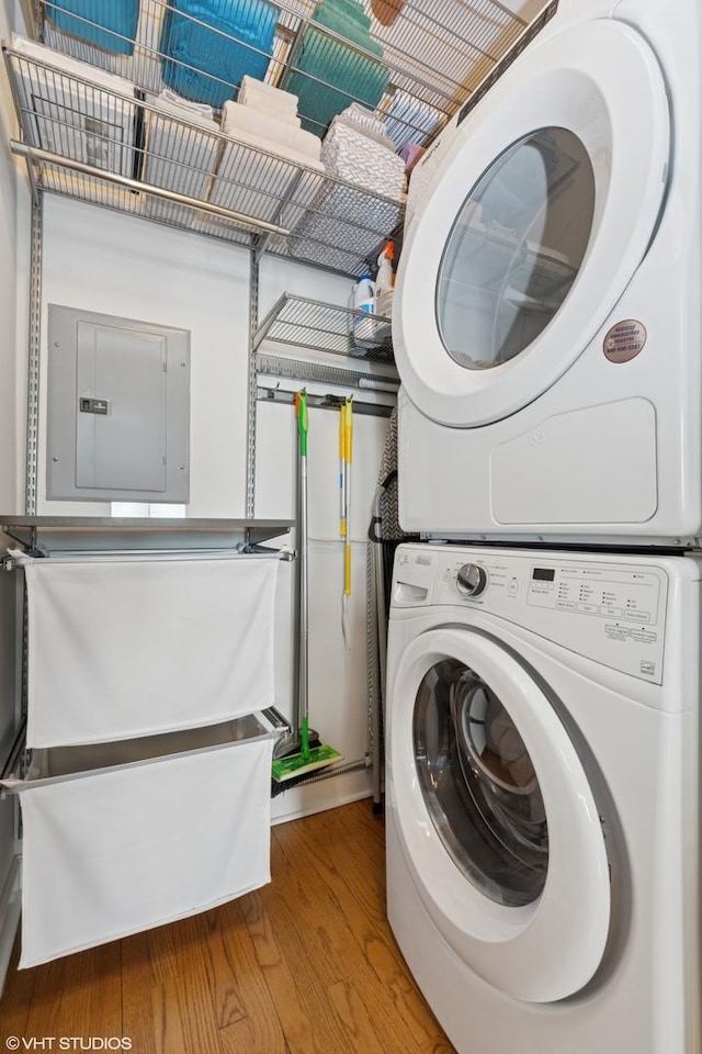 washroom featuring laundry area, light wood-style flooring, electric panel, and stacked washer and clothes dryer