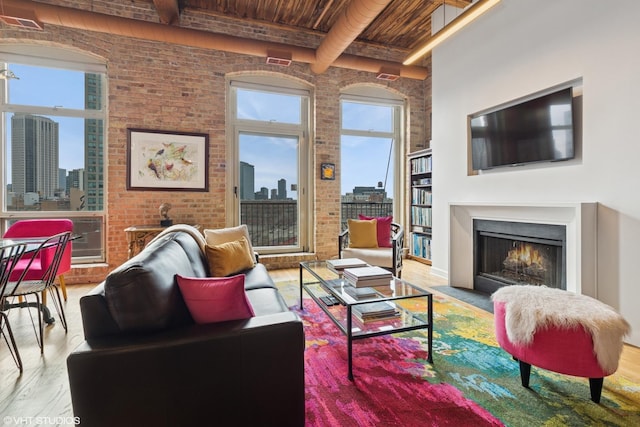 living area with wooden ceiling, brick wall, a fireplace with flush hearth, wood finished floors, and a view of city