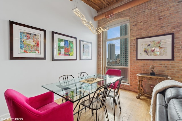 dining area with wood ceiling, brick wall, light wood-style flooring, and a city view