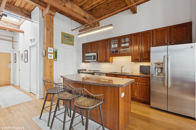 kitchen with a sink, appliances with stainless steel finishes, a center island, tasteful backsplash, and a kitchen bar