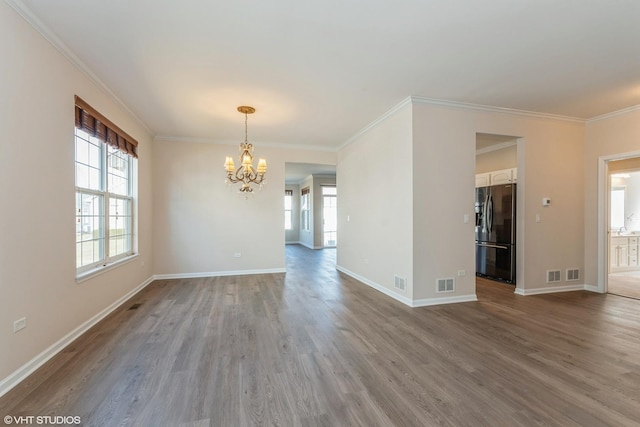 interior space featuring a chandelier, visible vents, ornamental molding, and wood finished floors