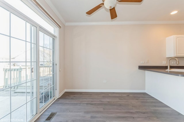 unfurnished dining area featuring visible vents, a ceiling fan, wood finished floors, and crown molding