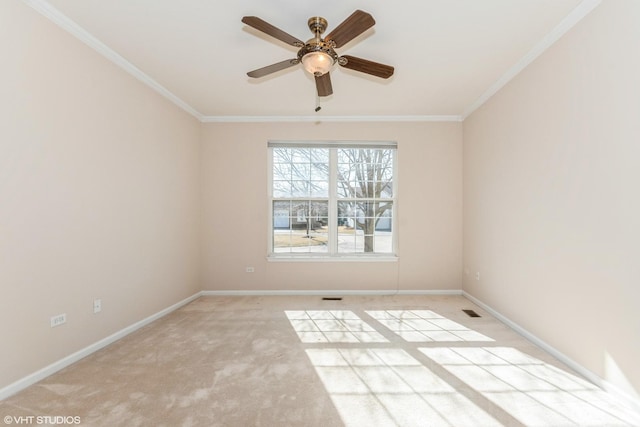 carpeted spare room with visible vents, baseboards, a ceiling fan, and ornamental molding