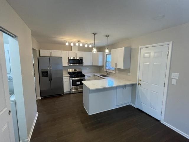 kitchen with dark wood-style floors, light countertops, appliances with stainless steel finishes, white cabinets, and a peninsula