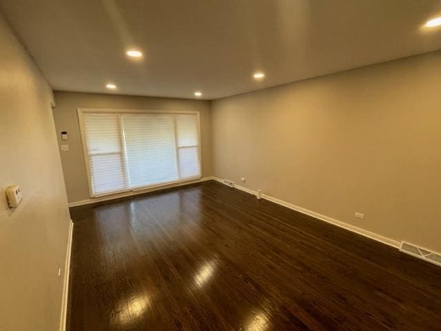 spare room with dark wood-type flooring, recessed lighting, visible vents, and baseboards