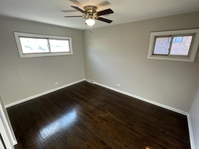 unfurnished room featuring dark wood-style floors, visible vents, a ceiling fan, and baseboards