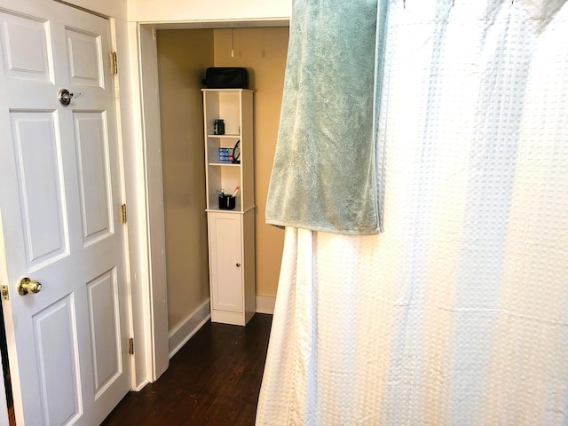 hall featuring dark wood-style flooring and baseboards