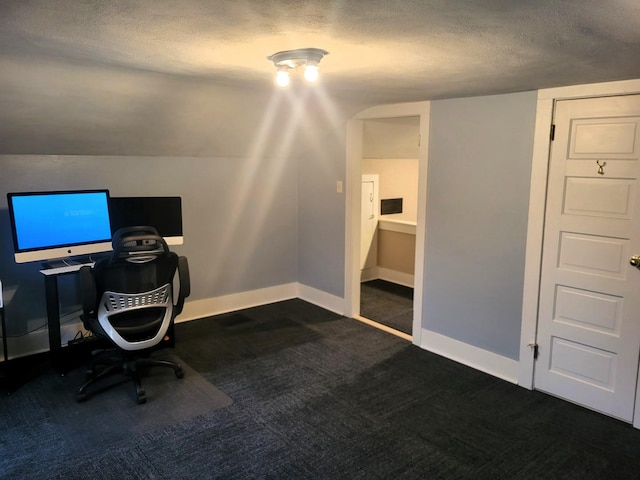 unfurnished office with vaulted ceiling, baseboards, dark carpet, and a textured ceiling