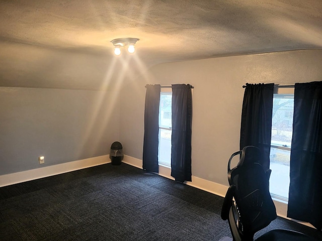 unfurnished office featuring vaulted ceiling, a textured ceiling, dark carpet, and baseboards