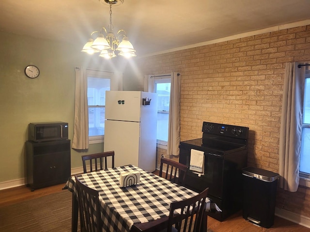 dining space featuring a chandelier, brick wall, wood finished floors, and baseboards