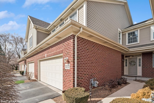 view of side of property with driveway, brick siding, and an attached garage