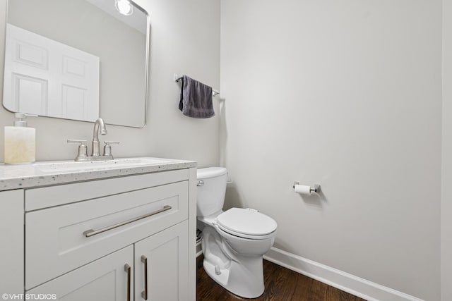 bathroom with toilet, baseboards, wood finished floors, and vanity