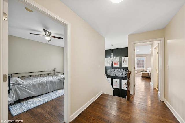 hall featuring a chandelier, baseboards, an upstairs landing, and wood finished floors