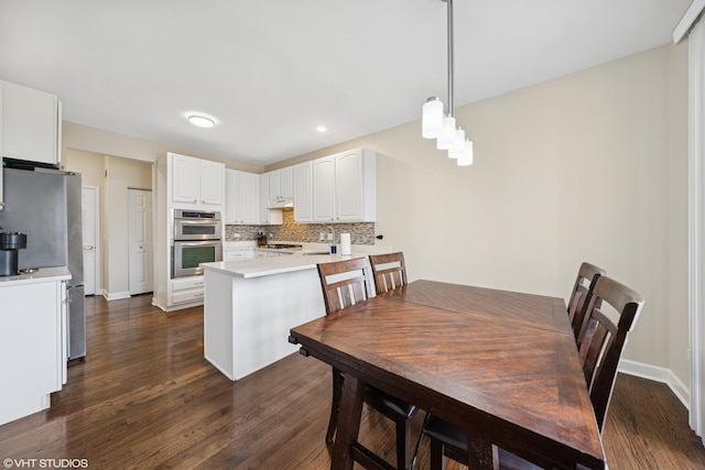 kitchen featuring a peninsula, dark wood-style flooring, white cabinets, appliances with stainless steel finishes, and tasteful backsplash