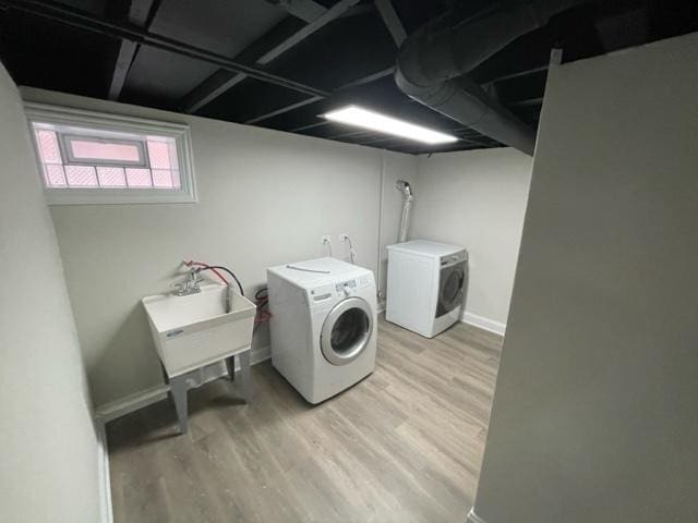 washroom featuring light wood-style floors, washing machine and dryer, laundry area, and a sink