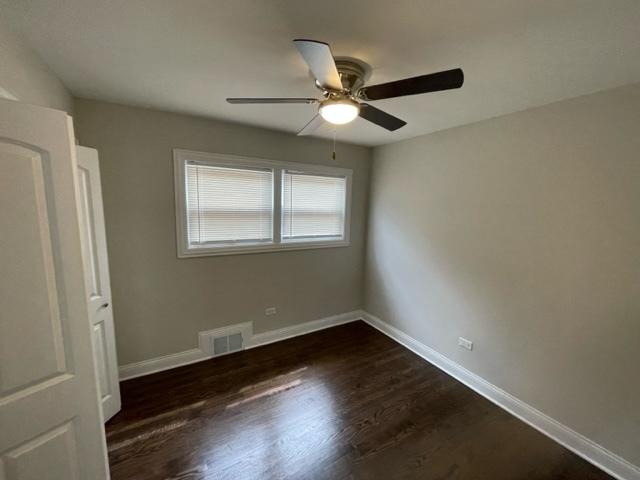 unfurnished bedroom with dark wood-type flooring, a ceiling fan, visible vents, and baseboards